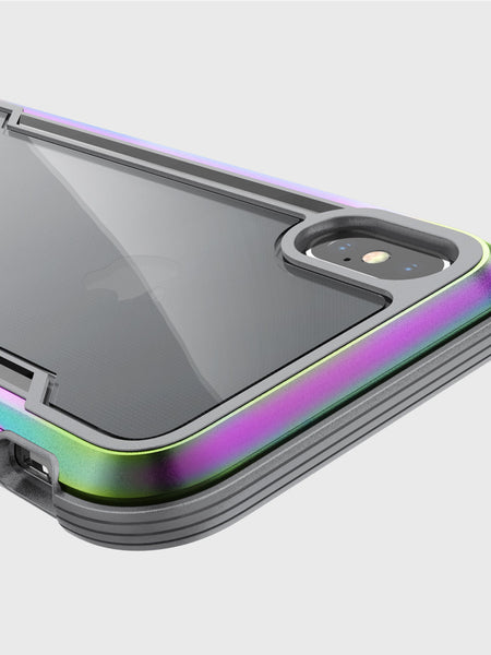 Close-up of an iPhone X/XS in a reflective, multi-colored Raptic SHIELD case, showcasing the camera and rear panel with military-grade drop protection.