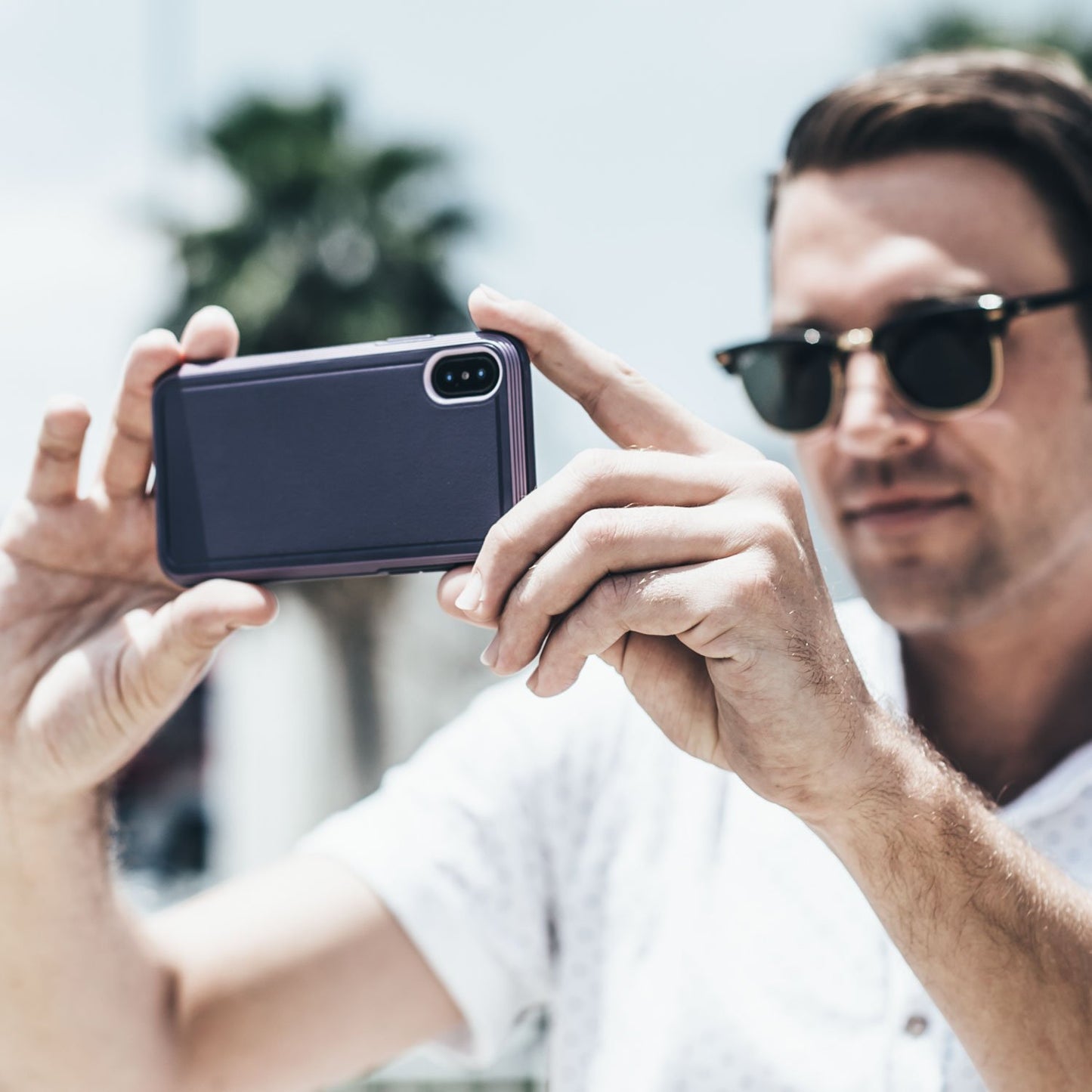 A man in sunglasses is taking a picture of his Raptic iPhone XR Case - ULTRA.