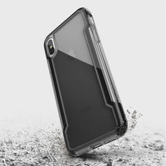 The Raptic iPhone XS Max Case - CLEAR is shown mid-fall with dust particles against a light gray backdrop. This transparent case delivers military-grade drop protection and features anti-yellowing and anti-scratch properties for lasting clarity and durability.