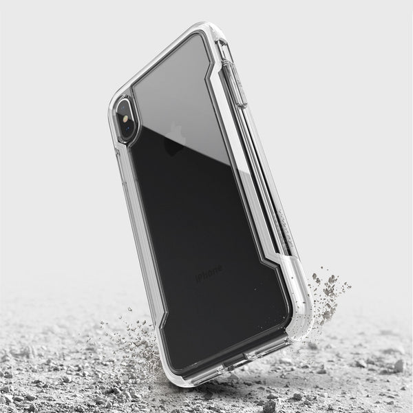 The Raptic iPhone XS Max Case - CLEAR, featuring transparent, anti-yellow, and anti-scratch protection, appears suspended above a cracked surface to demonstrate its military-grade drop protection.