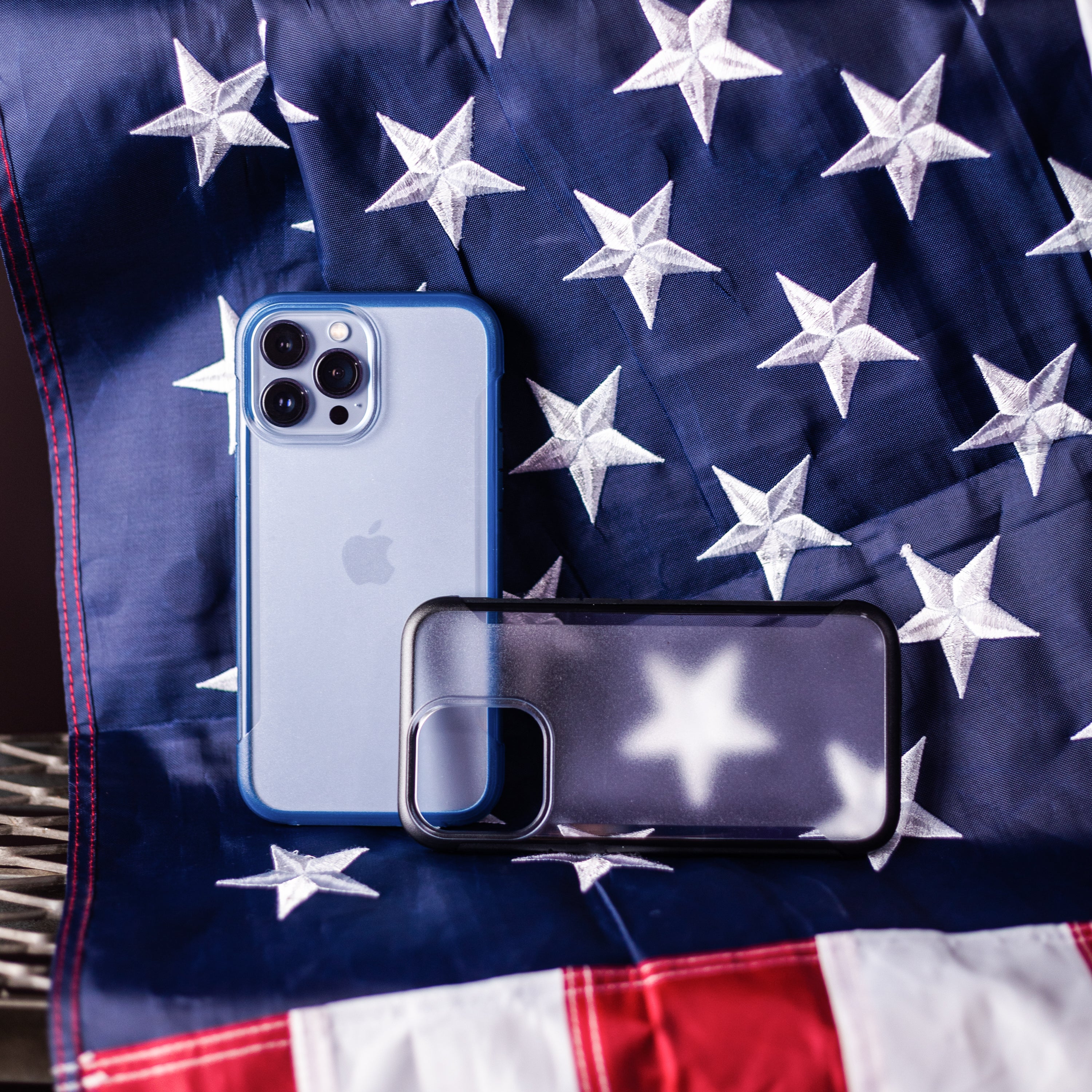 The eco-friendly iPhone 13 Pro Max Case - TERRAIN by Raptic is proudly displayed on top of an American flag.