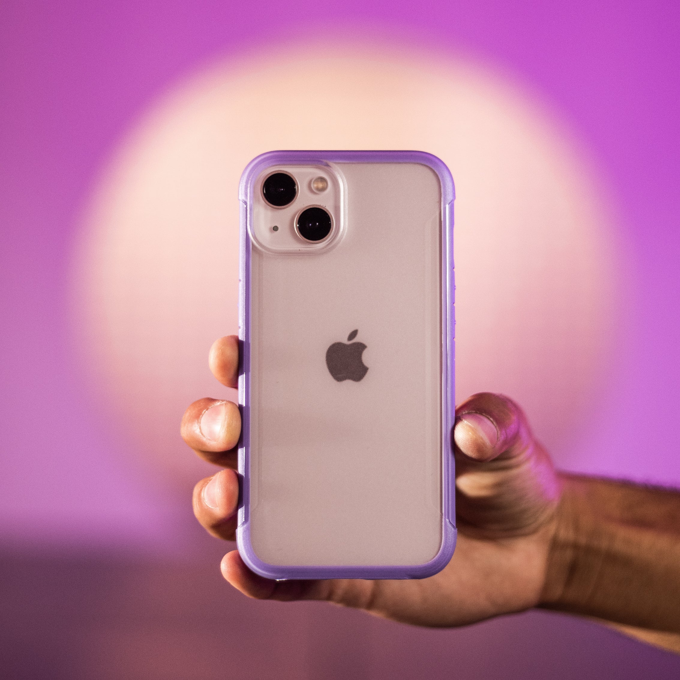 A person holding up an iPhone 13 Case - TERRAIN by Raptic with a purple background.