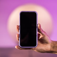 A hand holding up a Raptic TERRAIN iPhone 13 Case with a purple background.