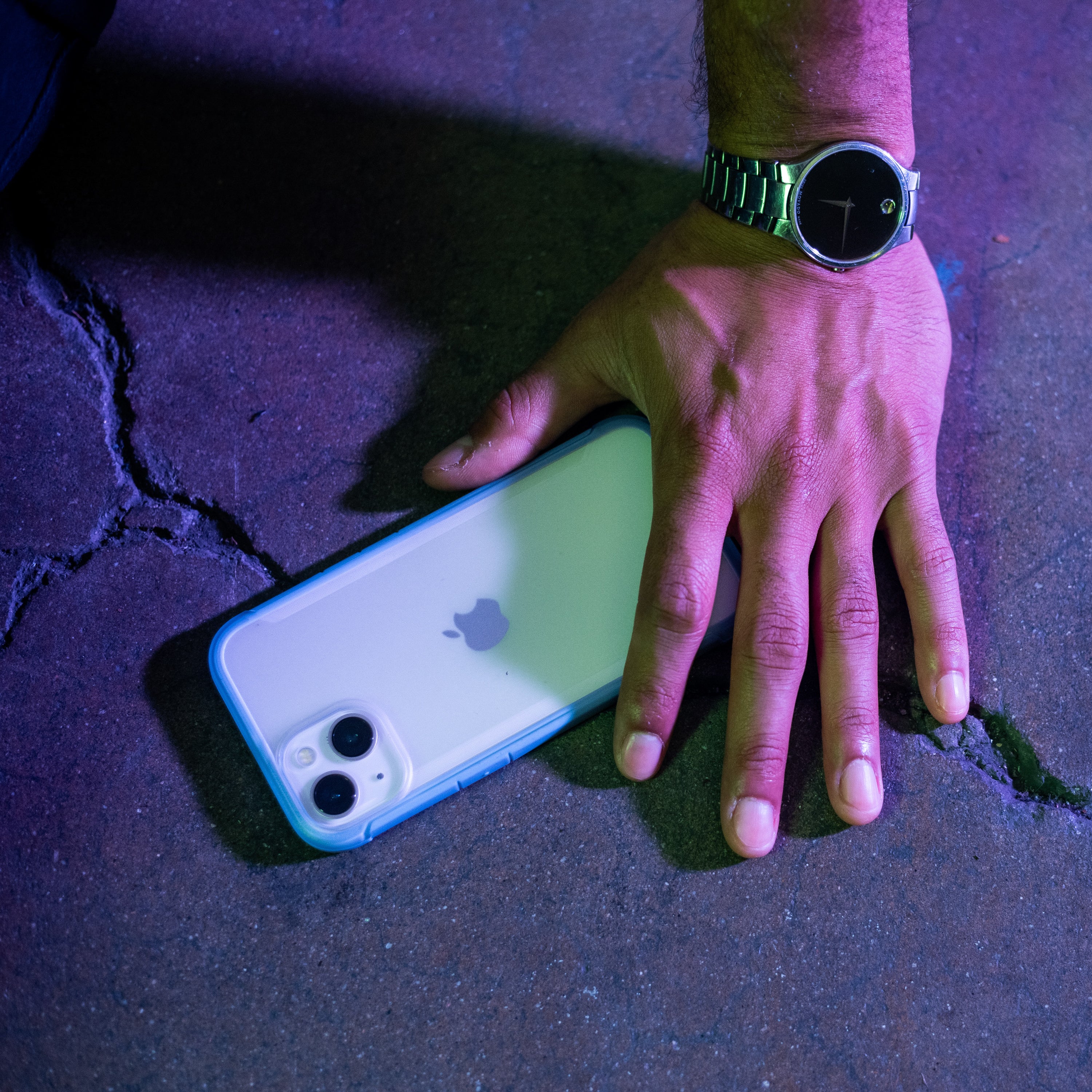 A man's hand holding a Raptic eco-friendly iPhone 13 Case - TERRAIN on a concrete floor.