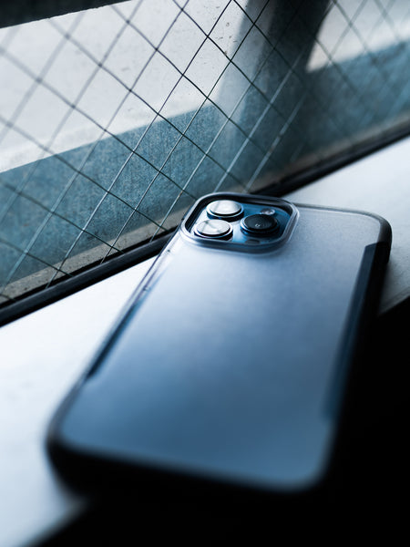 An iPhone 13 Pro Case - TERRAIN by Raptic is sitting on a eco-friendly window sill.