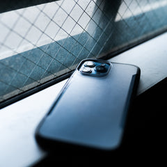 An iPhone 13 Pro Case - TERRAIN by Raptic is sitting on a eco-friendly window sill.